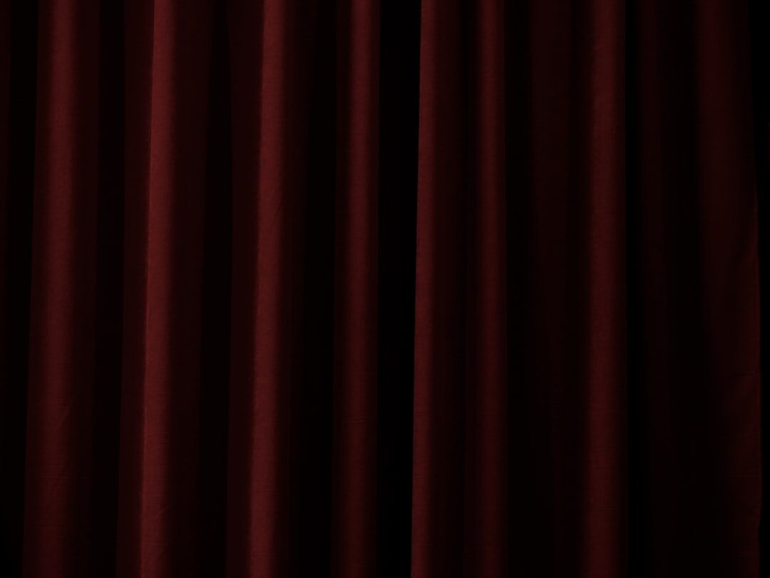 Ornate theatre interior with red velvet curtains and empty seats